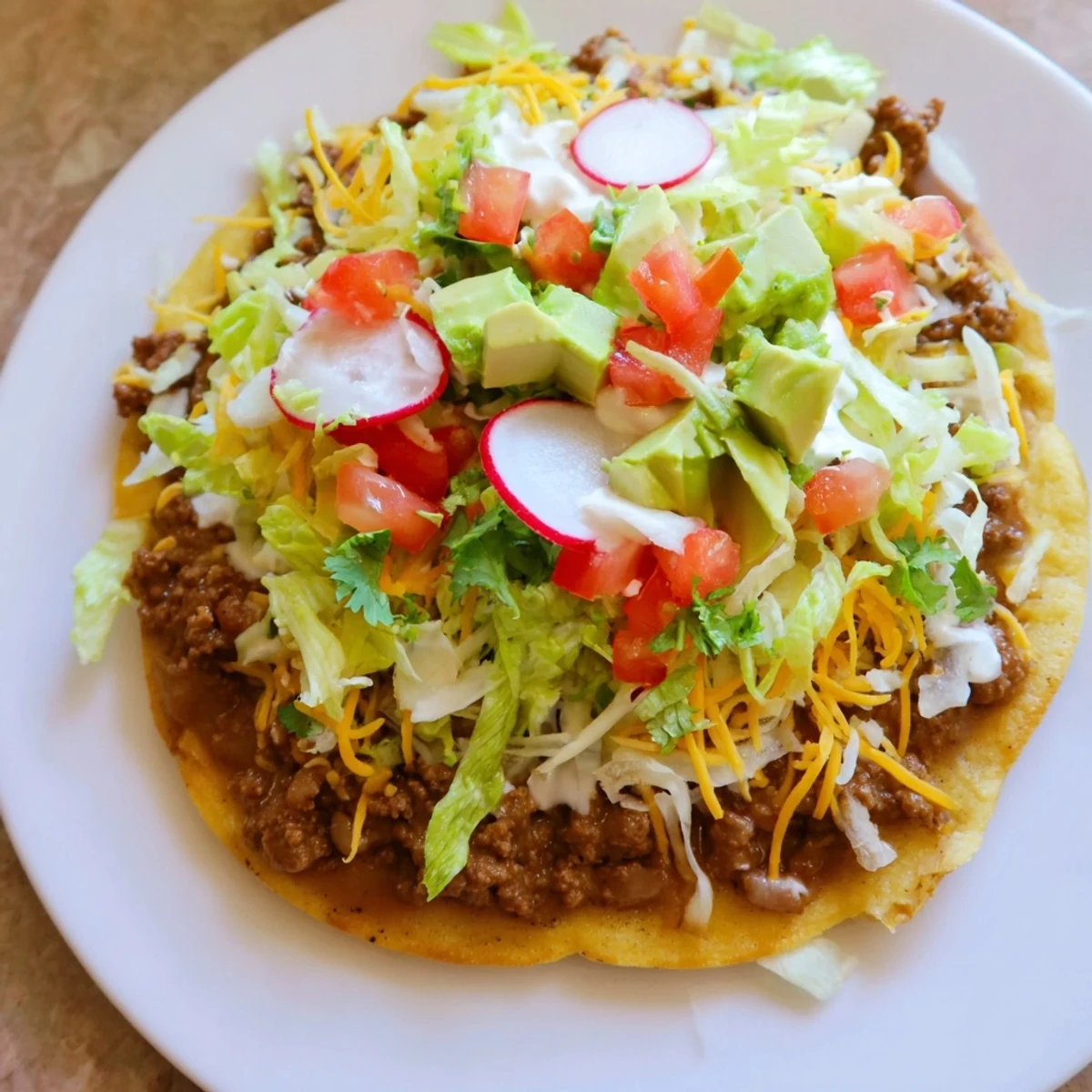 Crispy corn tostadas topped with seasoned ground beef and warm refried beans, ready to eat.