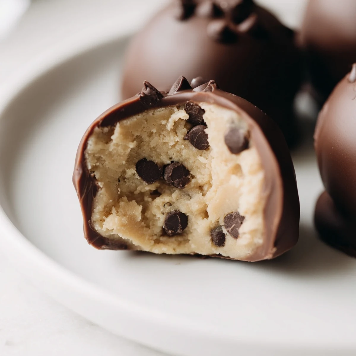 A small plate of bite-sized Chocolate Chip Cookie Dough Truffles served chilled, garnished with extra chocolate chips.