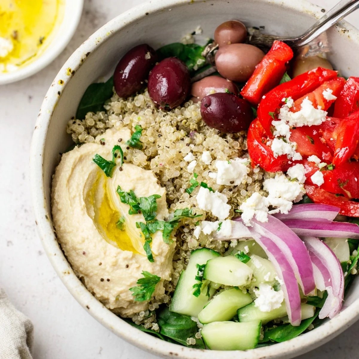 Freshly prepared Mediterranean Quinoa Bowl featuring fluffy quinoa, hummus, kalamata olives, and colorful, crisp vegetables.
