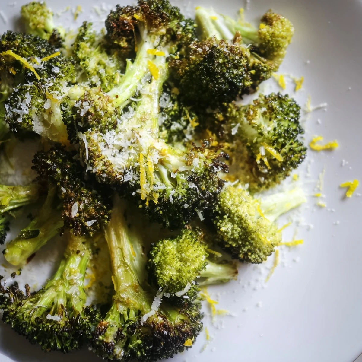 Sizzling roasted broccoli with garlic and Parmesan on parchment, finished with lemon zest.