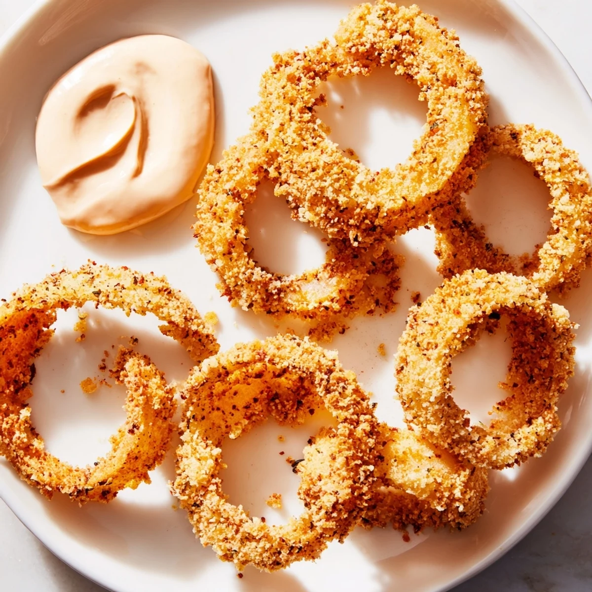 Crispy Air Fryer Onion Rings with Spicy Burger Sauce stacked high with a creamy dip.