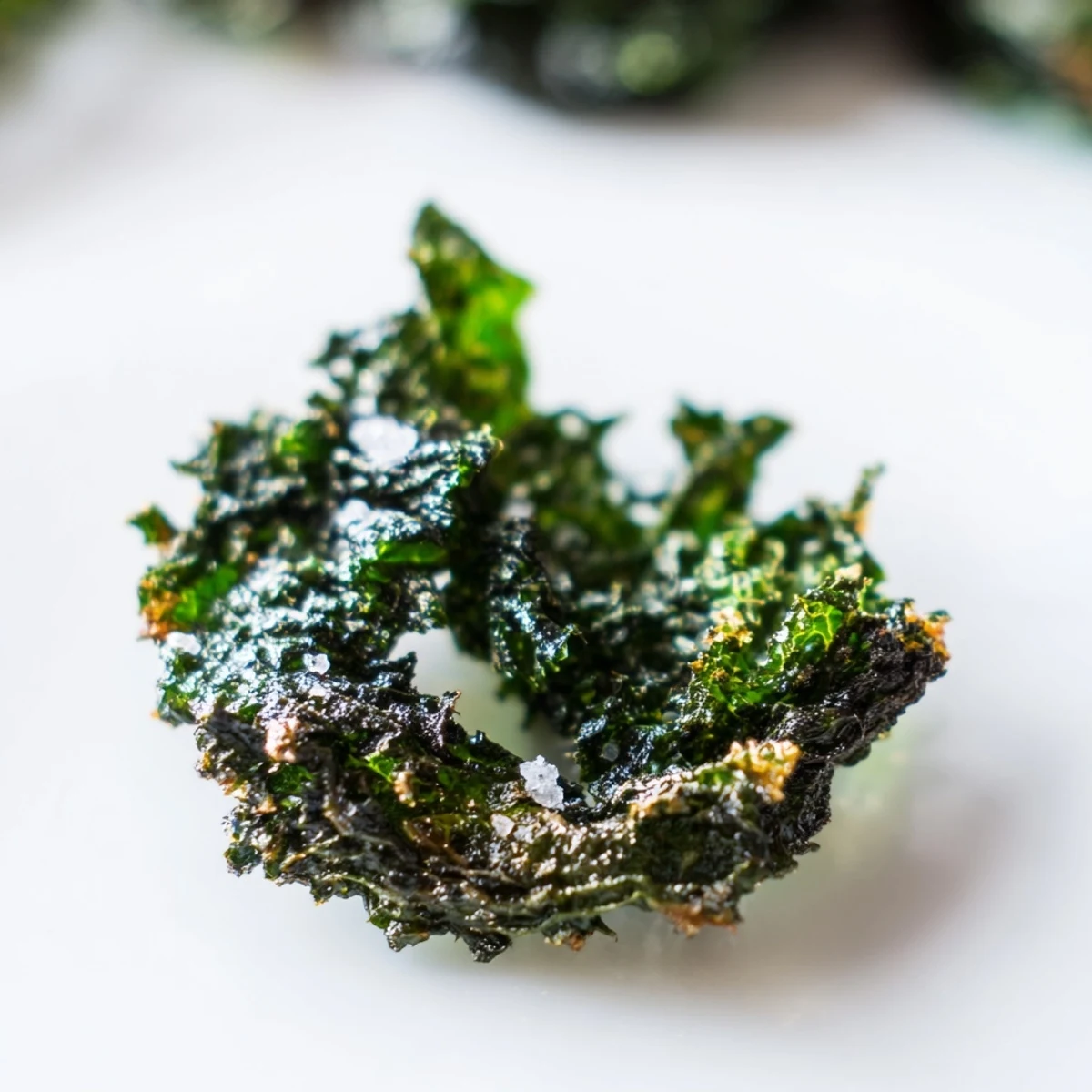 Golden, oven-baked Green Kale Chips with Sea Salt stacked on a plate, ready to enjoy as a crunchy vegan snack.