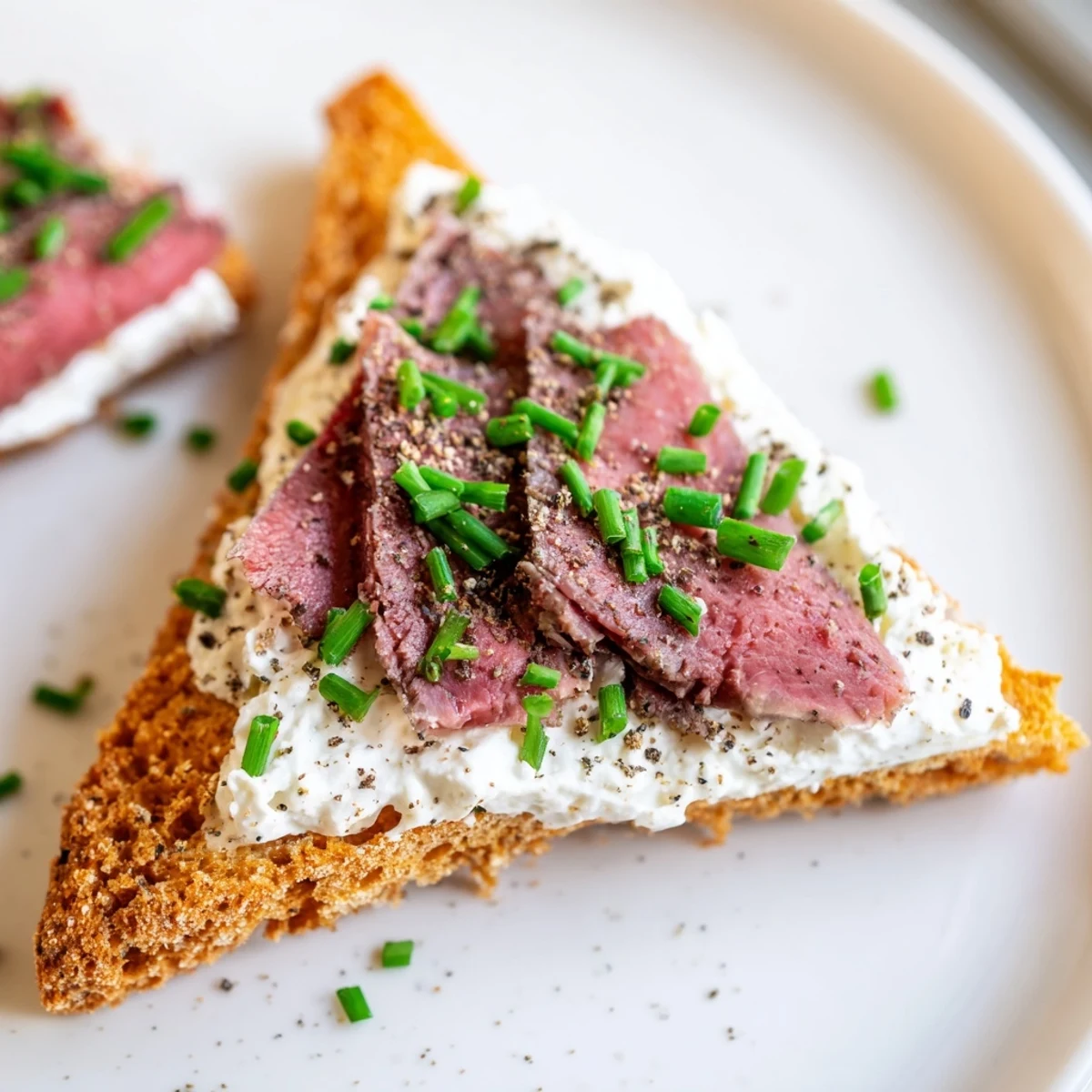 Crisp toast points topped with folded beef and fresh herbs, a perfect bite-sized appetizer for gatherings.