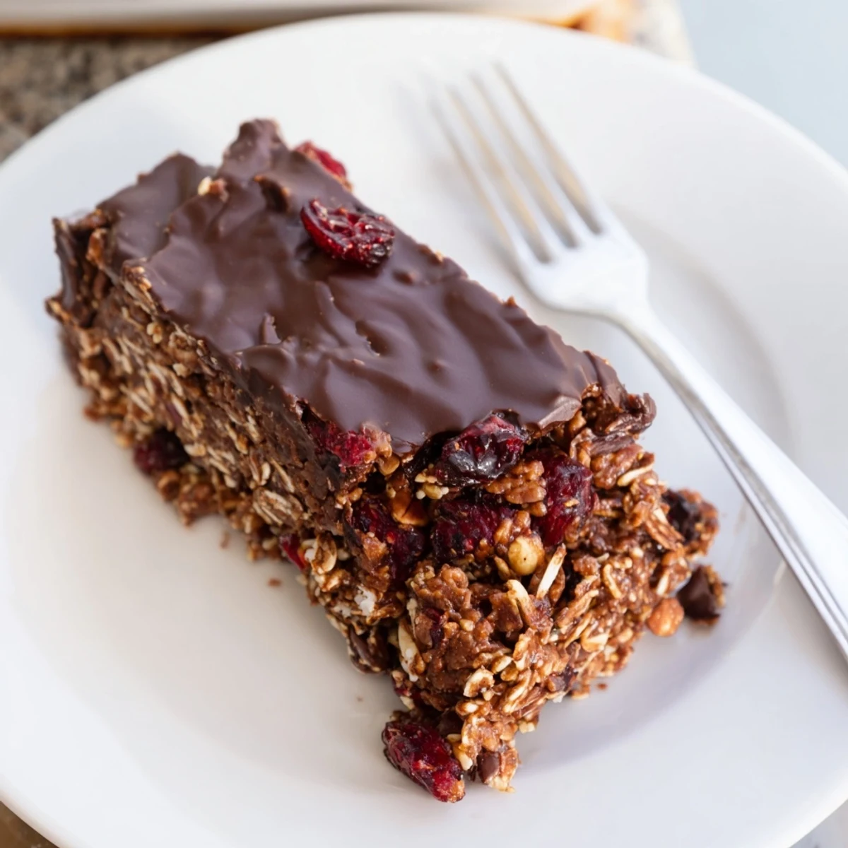 The finished Chocolate Lunch Bar Snack shows a rich, glossy chocolate topping on a hearty base, cut into 12 squares.