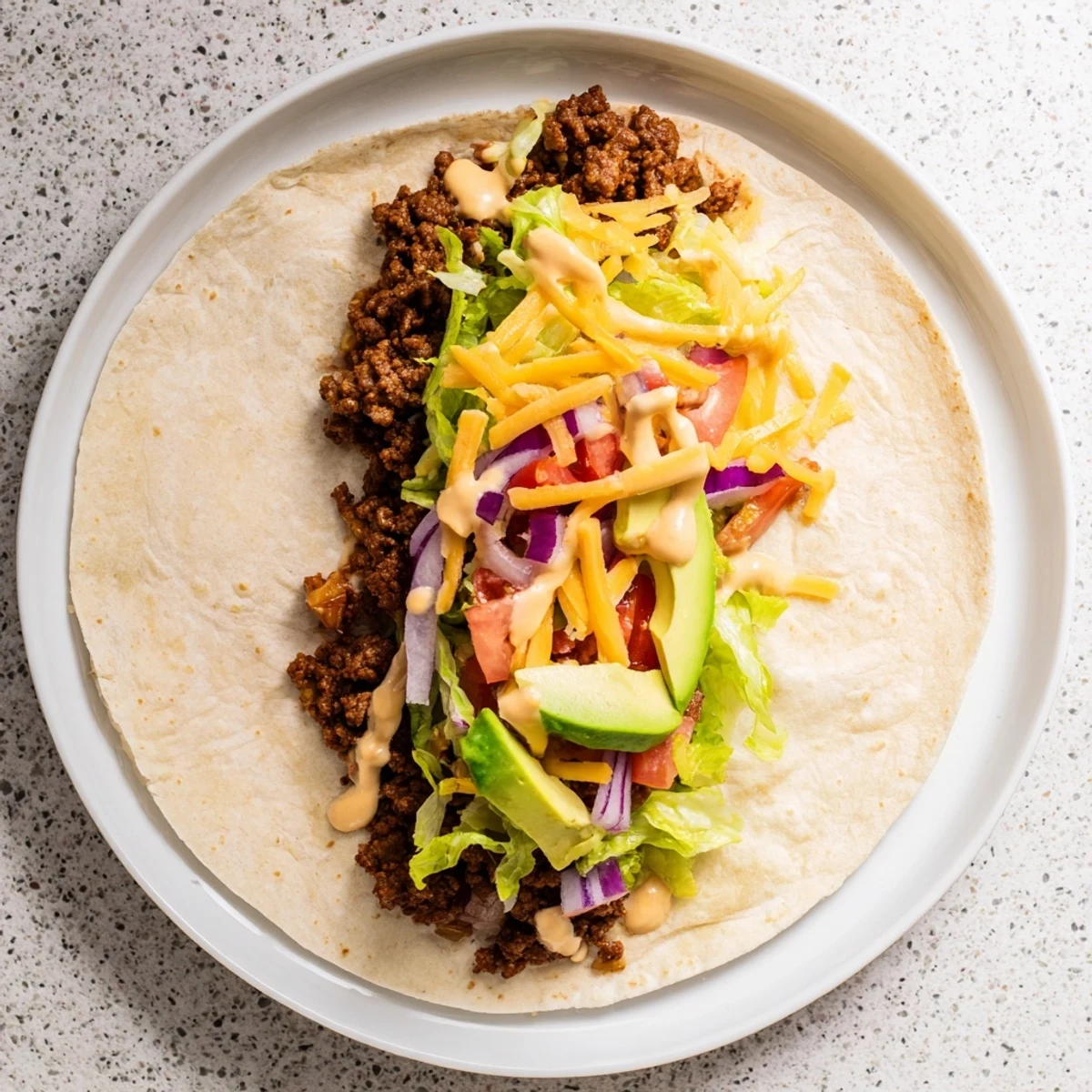 Four freshly assembled Beef Lunch Wrap Tortillas are cut in half, revealing layers of creamy sour cream sauce, vibrant vegetables, and hearty seasoned beef filling.