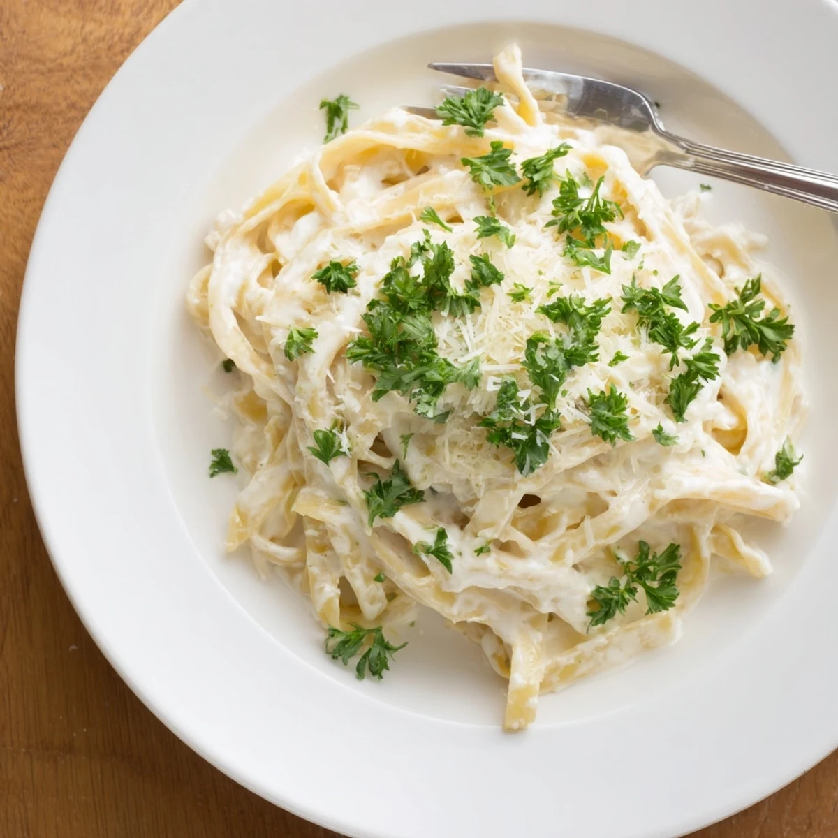 Warm skillet of homemade creamy dinner pasta sauce, featuring fresh parsley and melted Parmesan swirls.