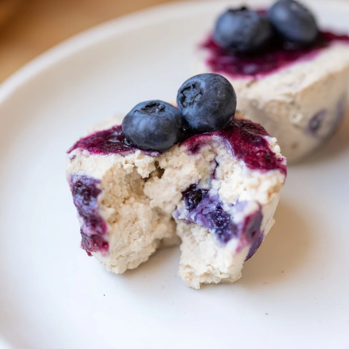 Fresh Blueberry Cheesecake Protein Bites arranged neatly in a row, with a dollop of blueberry compote on each.