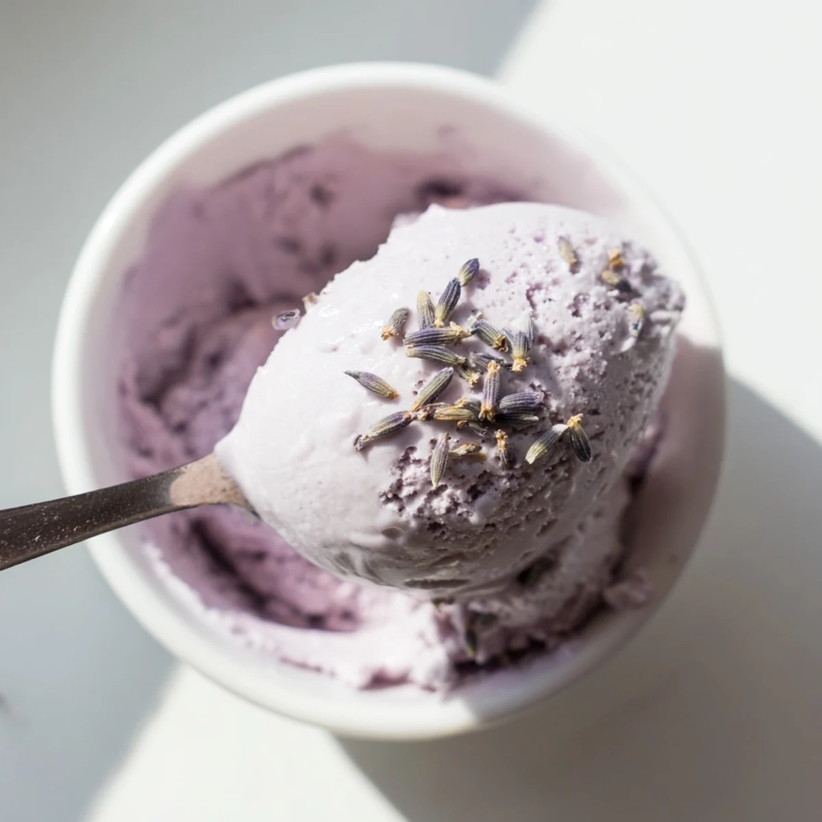 A bowl of Lavender Ice Cream paired with shortbread cookies on a sunny patio table.