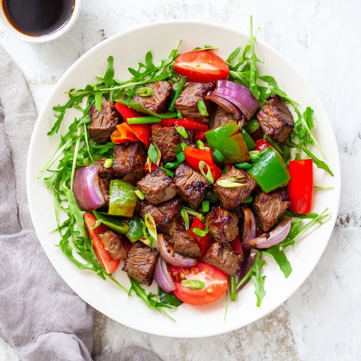 Vibrant Vietnamese Shaking Beef sizzles in a wok with crisp bell peppers and onions beside fresh watercress.