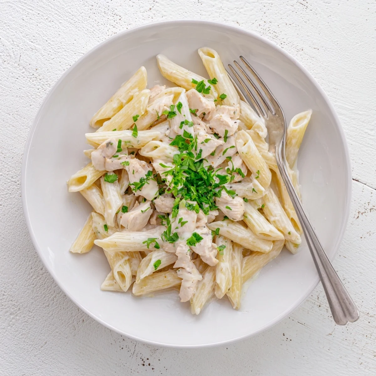 Creamy Crockpot Garlic Parmesan Chicken Pasta in a slow cooker, garnished with parsley.