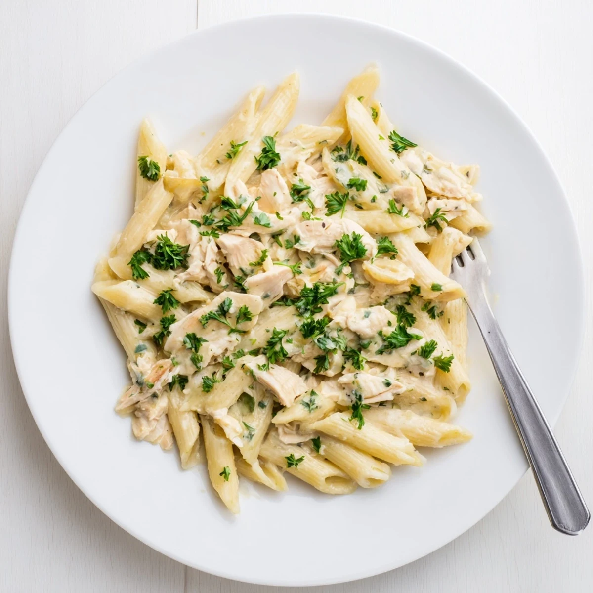 Hearty Crockpot Garlic Parmesan Chicken Pasta plated with steam rising and pasta noodles.