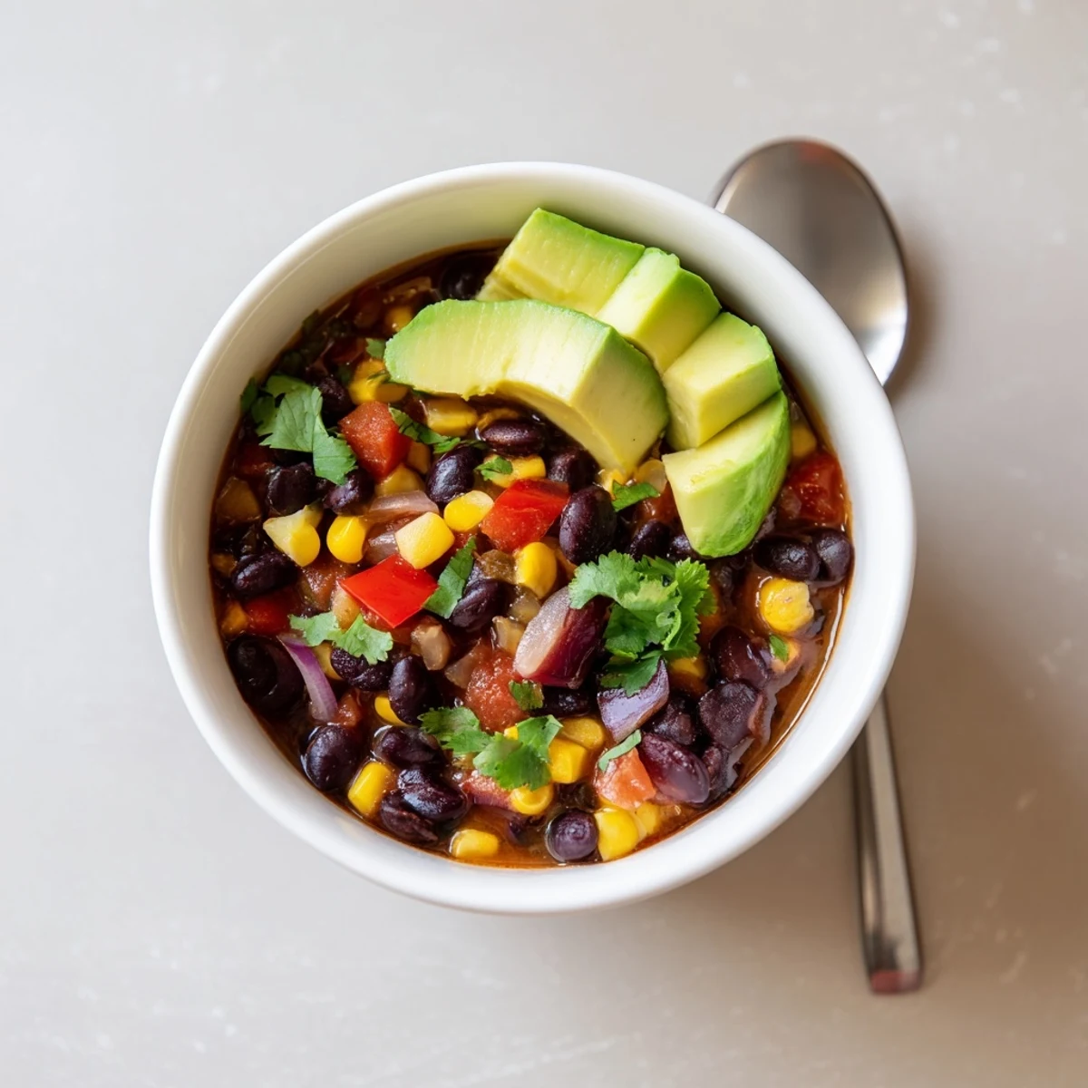 Freshly ladled Black Bean Corn Chili Lime Delight in a rustic bowl with cilantro and avocado.