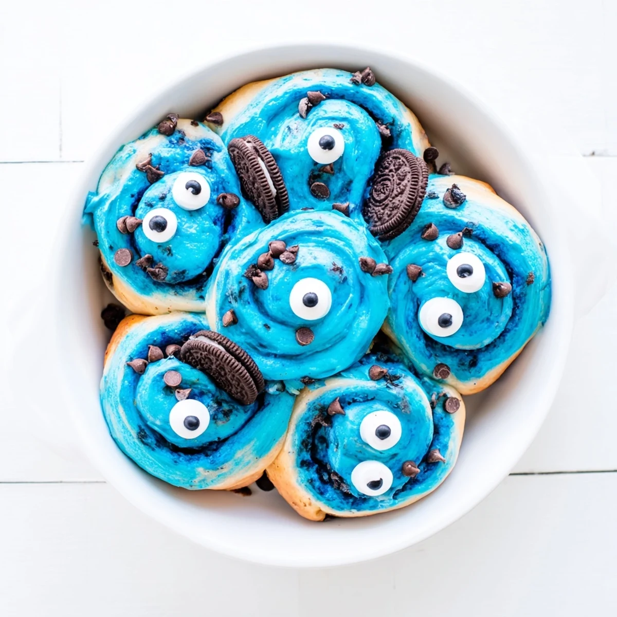 Freshly baked blue Cookie Monster Cinnamon Rolls on a plate, ready to be served with a glass of cold milk.