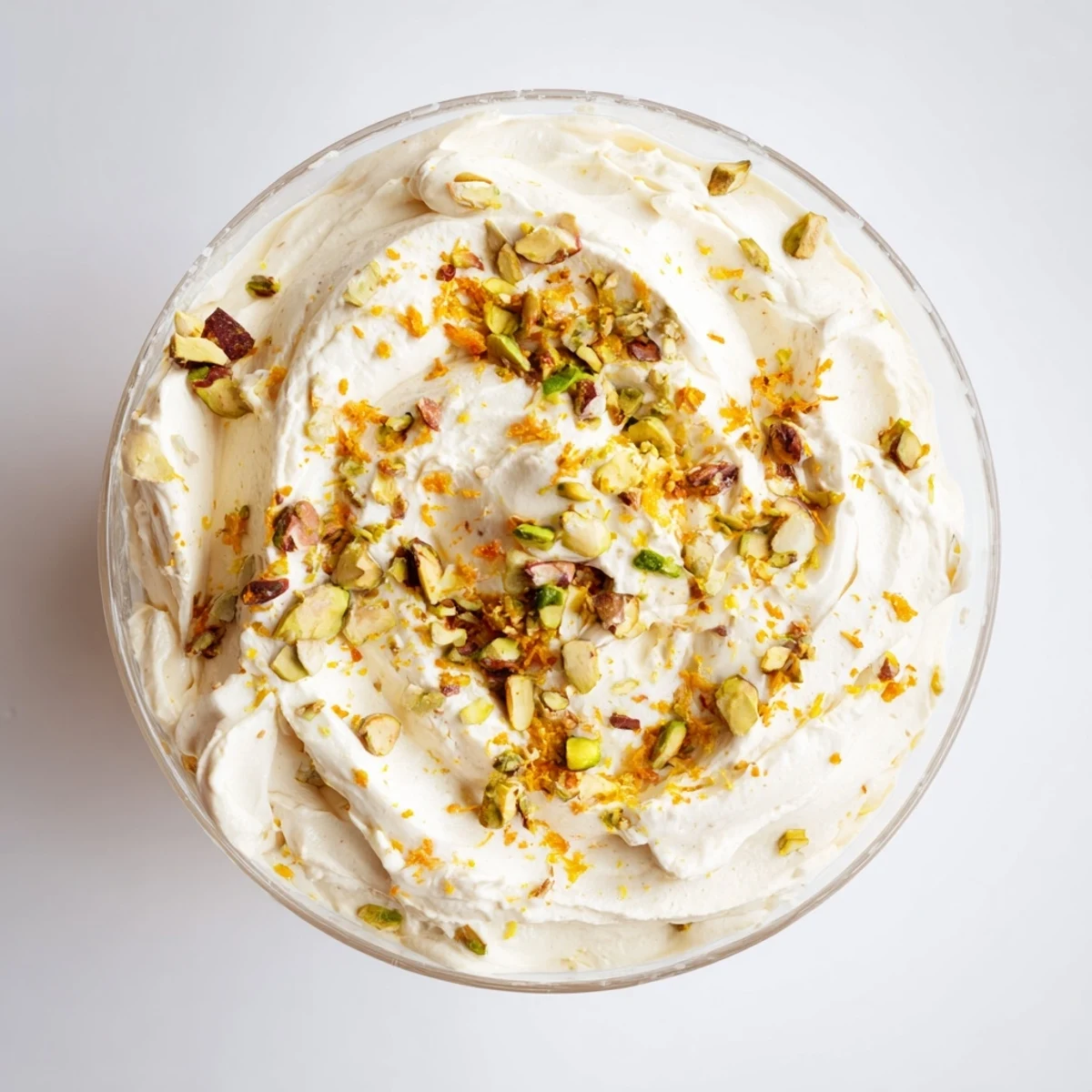 A clear close-up of Lebanese Date Orange Blossom Mousse in a glass with pistachios and orange zest.