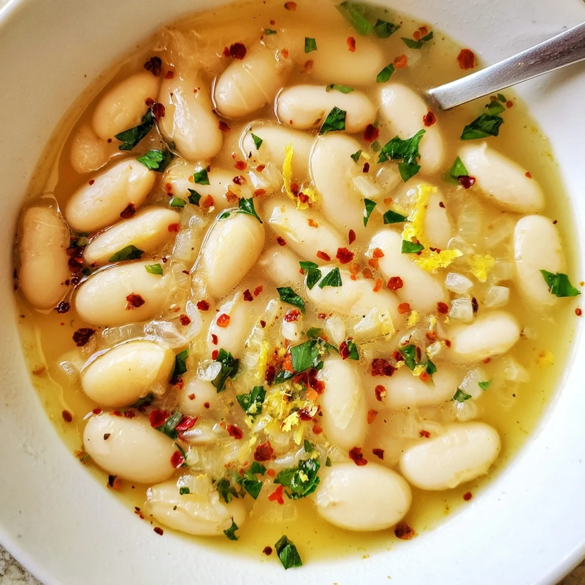 Creamy white beans floating in savory miso-butter broth garnished with fresh green herbs