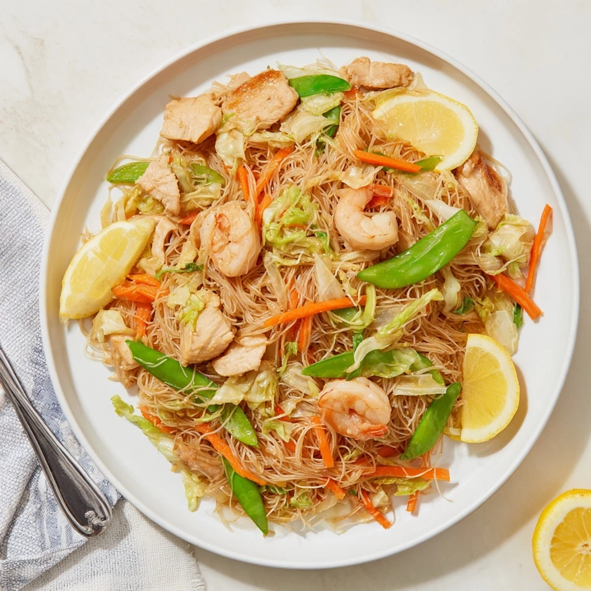 Close-up of traditional Pancit Bihon showcasing thin rice noodles tossed with chicken and shrimp in soy sauce