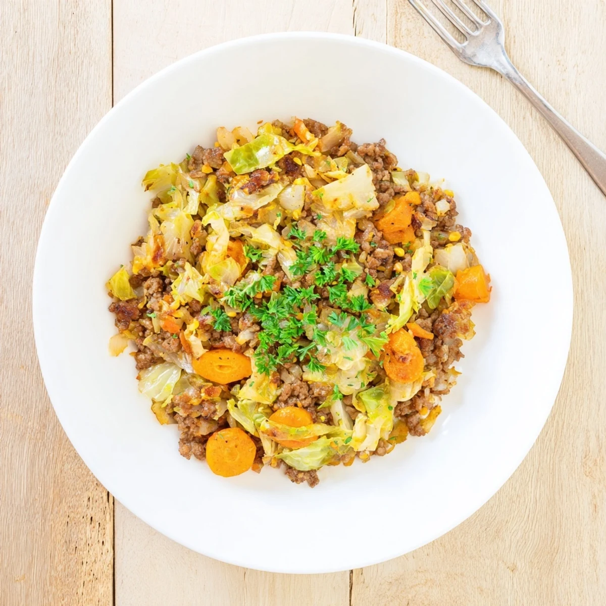Hearty ground beef and cabbage skillet dish featuring caramelized onions carrots and fragrant thyme seasoning