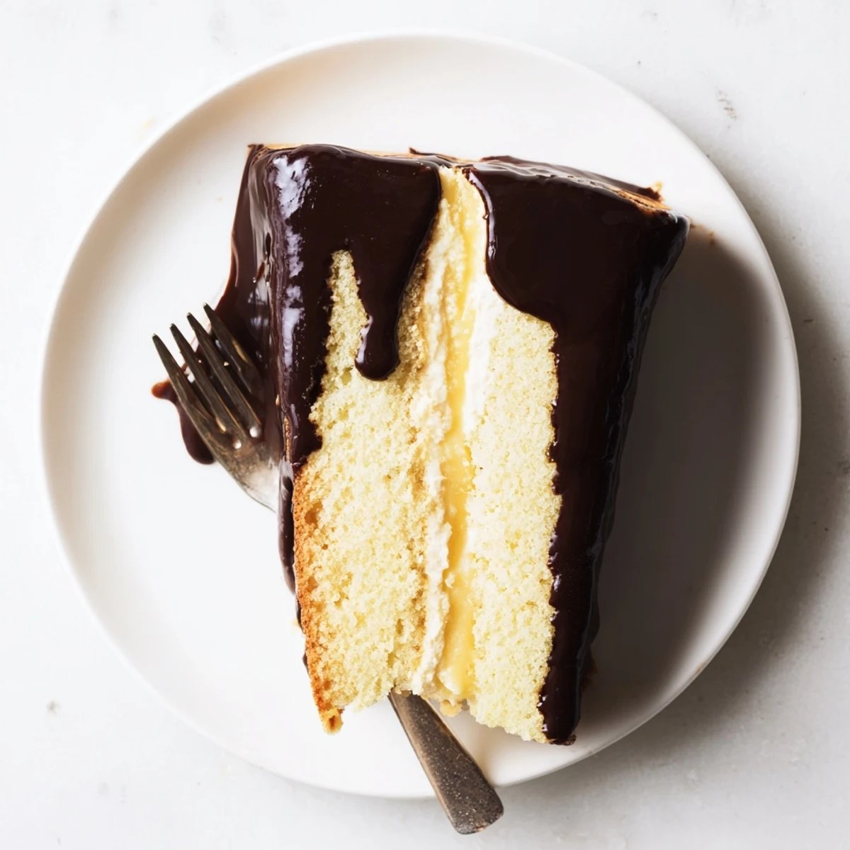 Chocolate-glazed Classic Boston Cream Pie sliced to show luscious pastry cream filling
