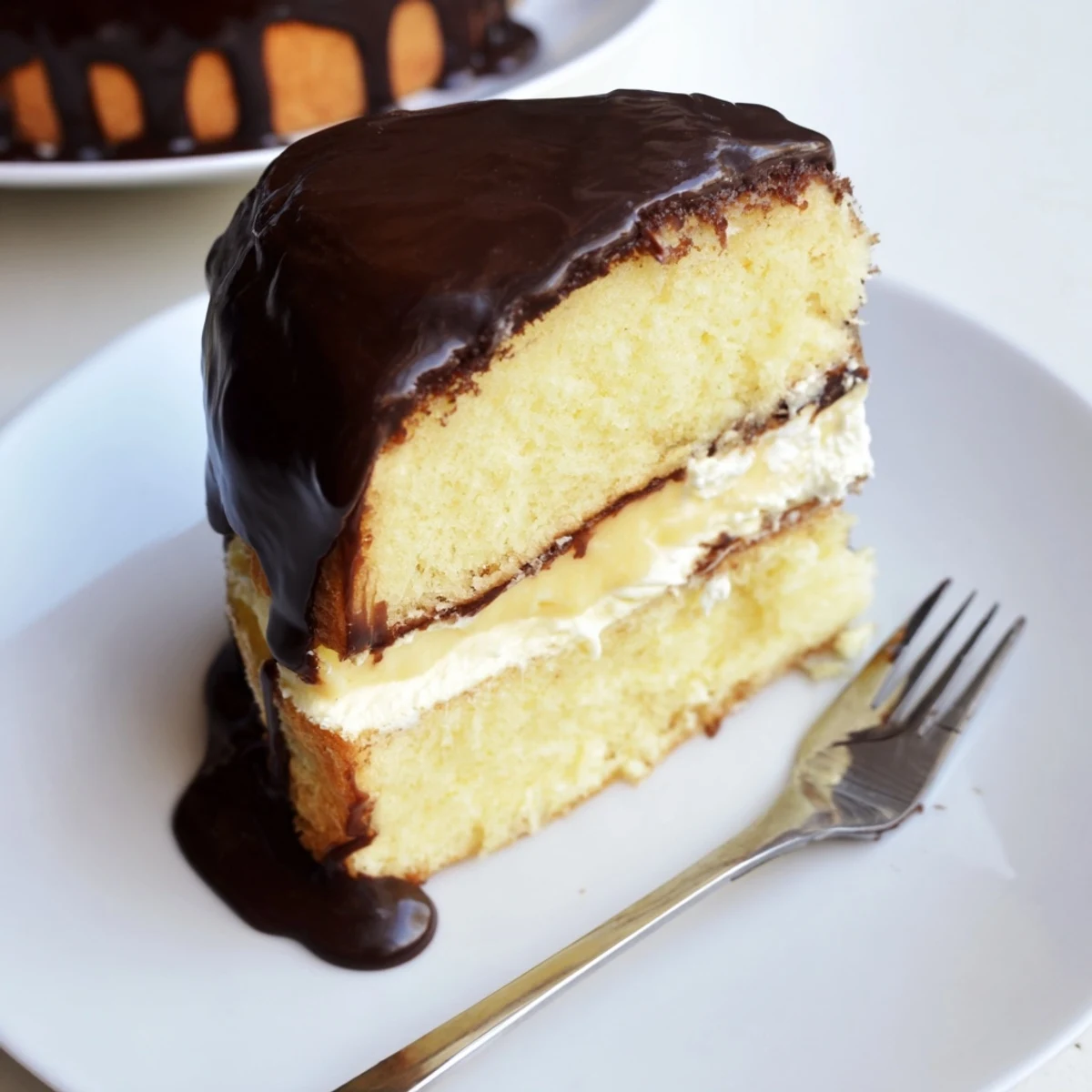 Homemade Classic Boston Cream Pie with glossy chocolate topping and silky vanilla center