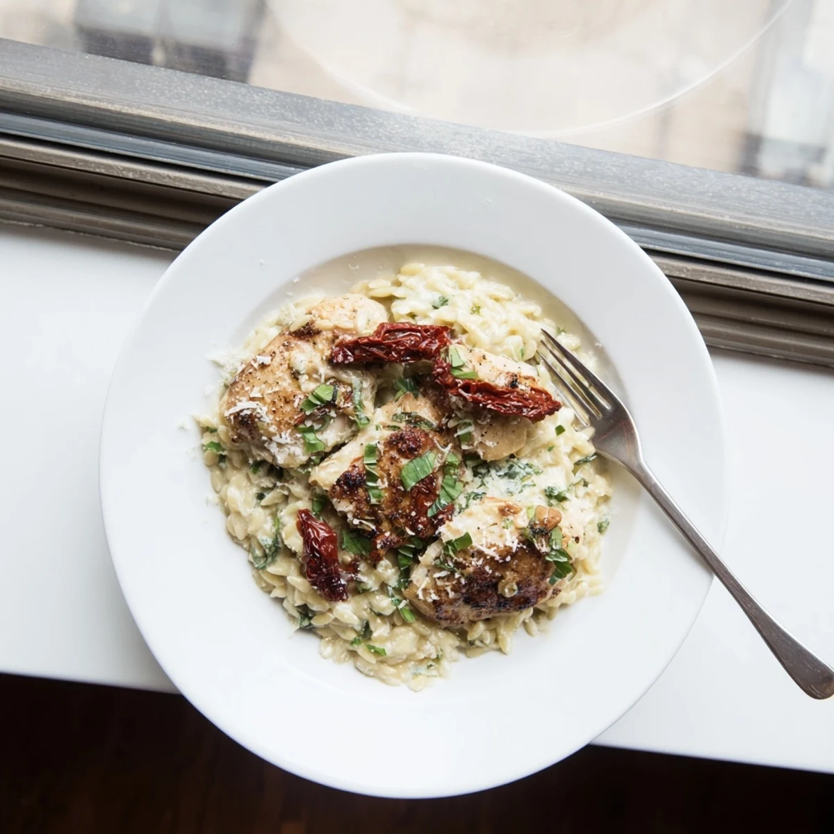 Golden chicken breasts nestled in tender orzo pasta with savory sun-dried tomatoes and fresh herbs in a creamy white sauce.