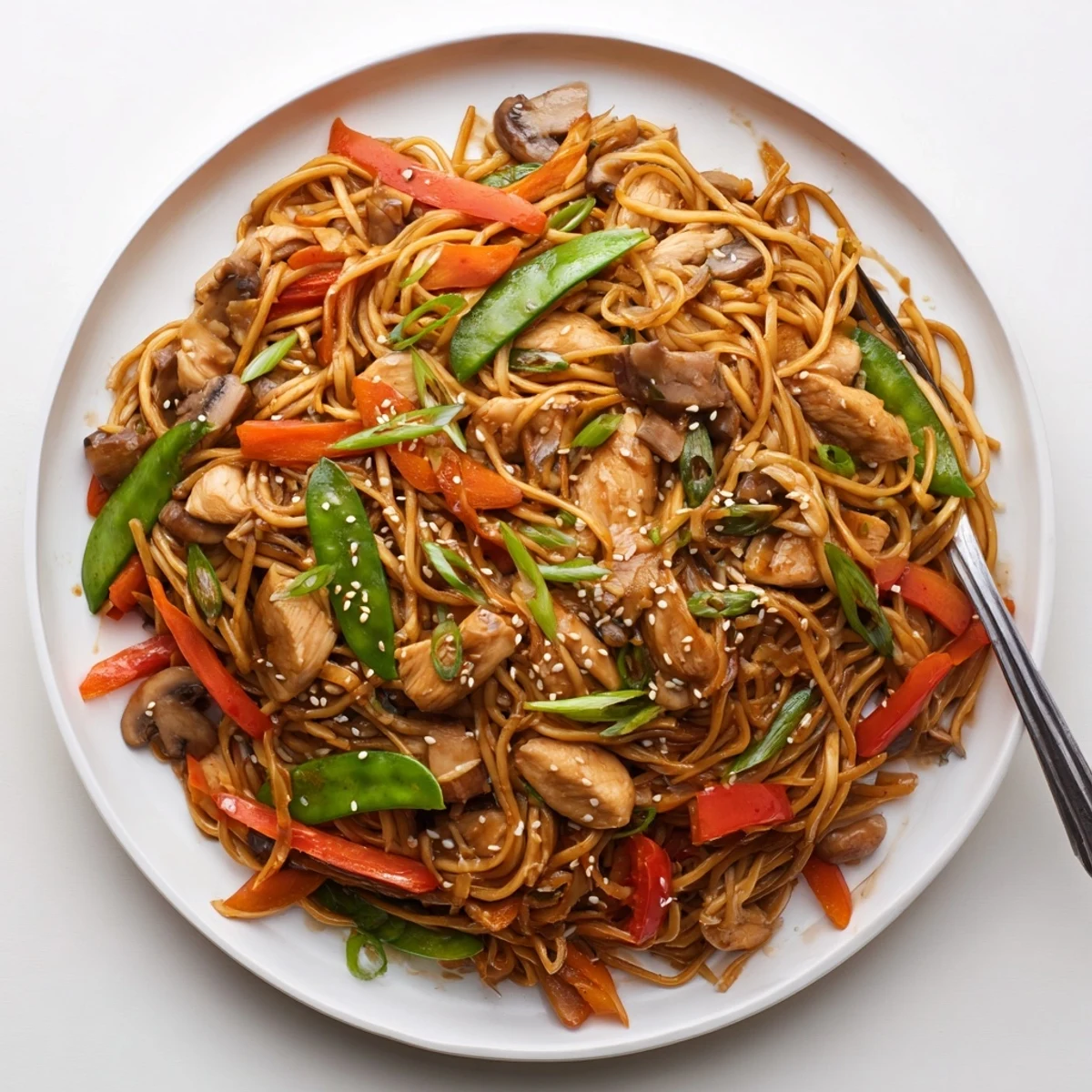 Plate of easy Crockpot Chicken Lo Mein garnished with sesame seeds and fresh green onions