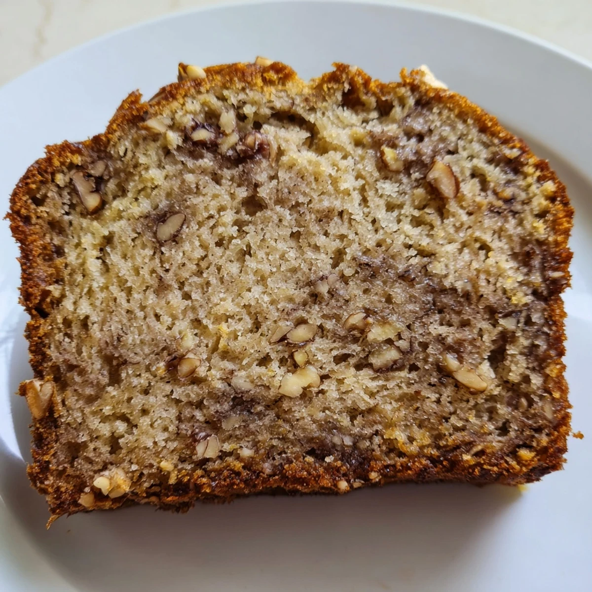 Slice of moist ultimate banana nut bread revealing generous chunks of walnuts throughout the tender crumb