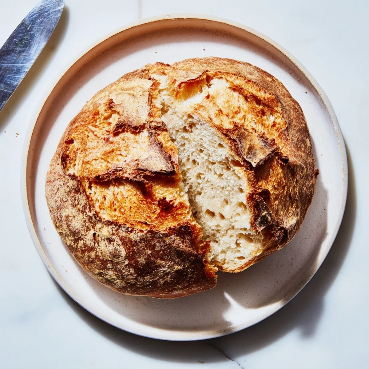 Golden artisan crusty bread with crackling crust and airy chewy interior, fresh from oven