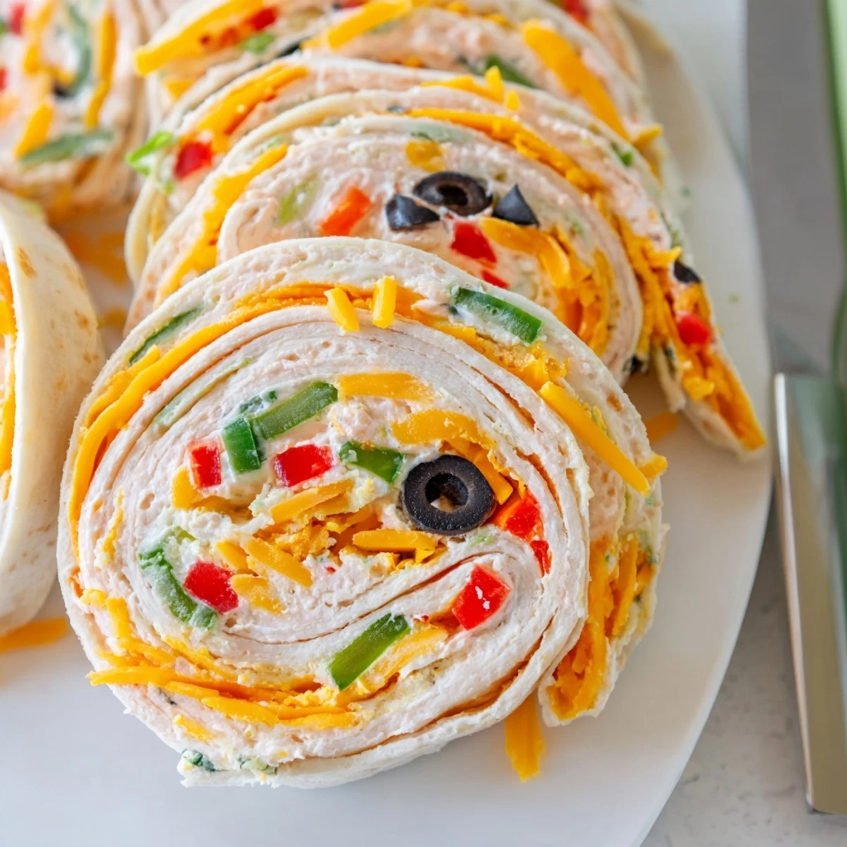 Easy tortilla pinwheels featuring colorful red peppers, green onions, and creamy cheddar cheese spread rolled inside soft flour tortillas