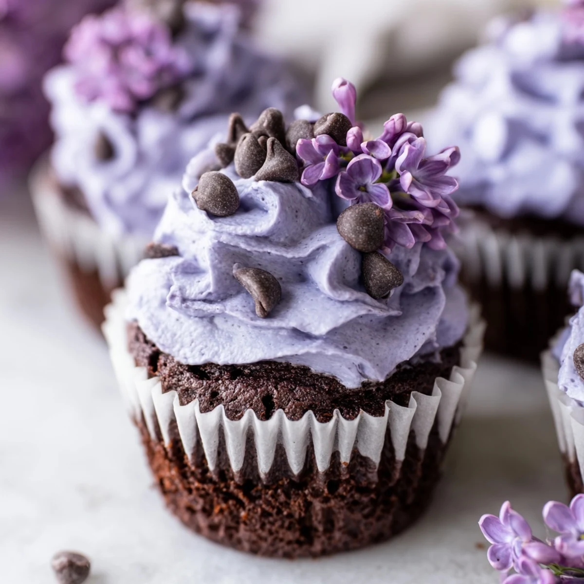 Rich chocolate cupcakes infused with delicate lilac flavor, garnished with edible flowers for spring