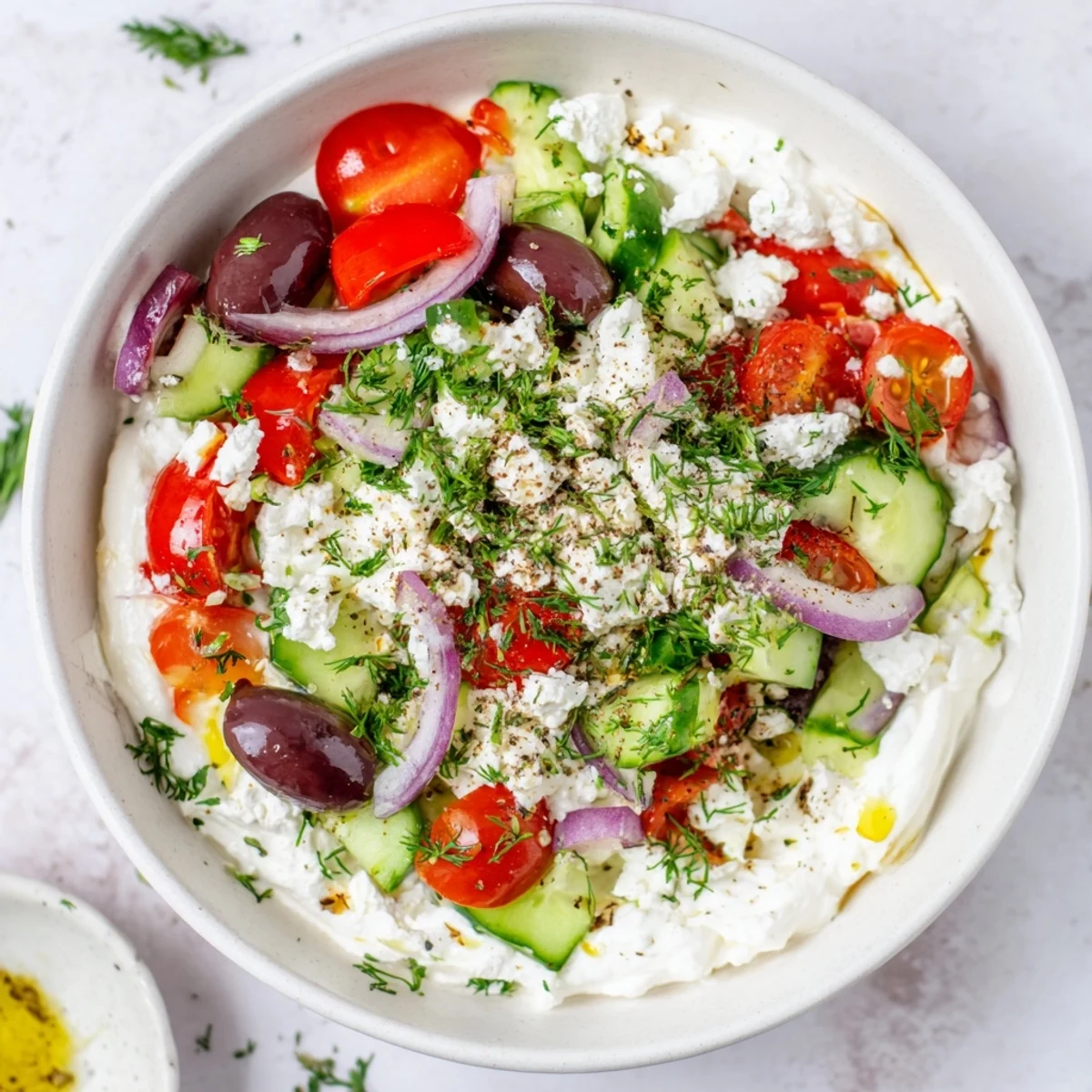 Greek salad cottage cheese bowl featuring colorful vegetables, olives, and crumbled feta in a serving dish