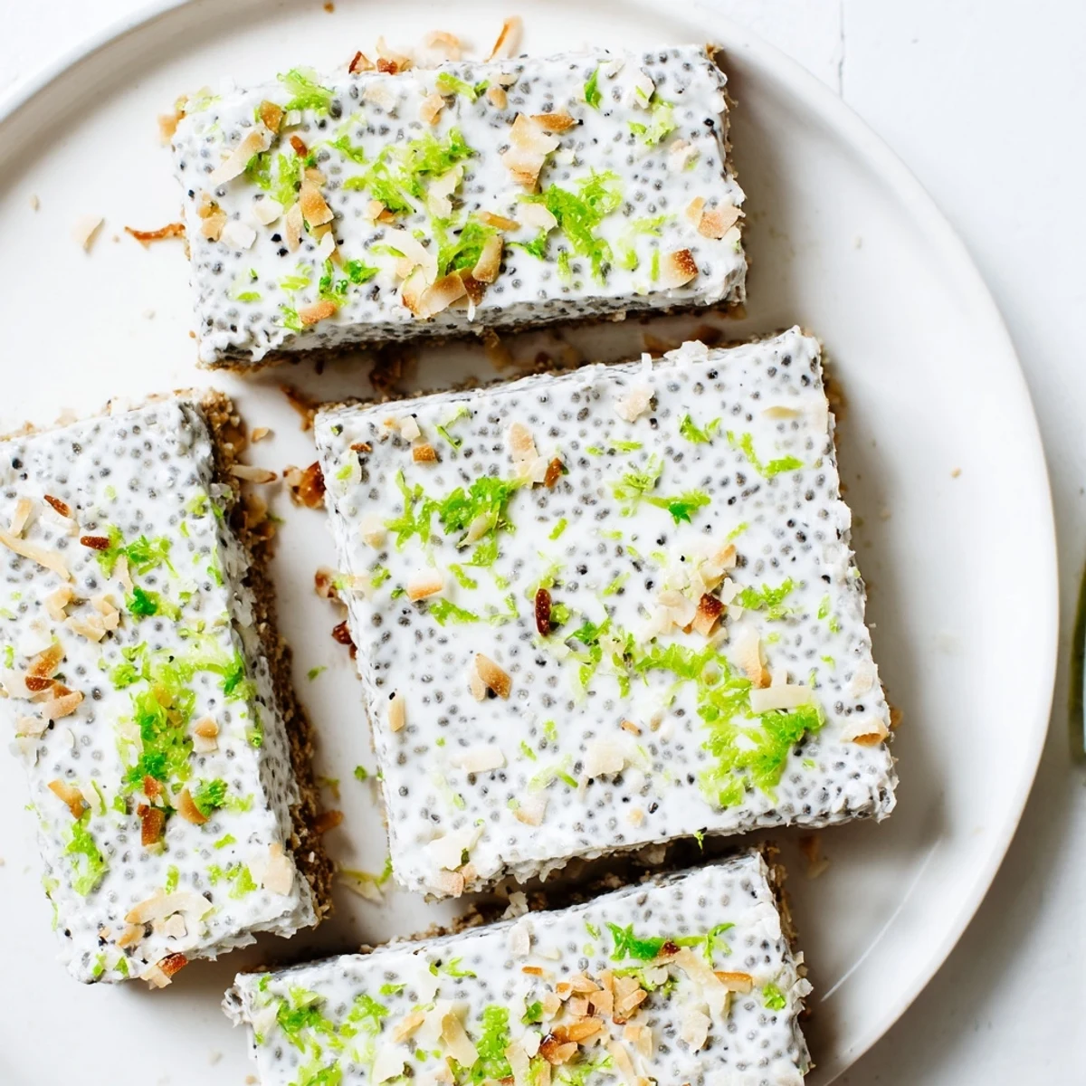 Square pan of zesty coconut lime chia pudding bars topped with toasted coconut flakes and fresh lime zest garnish