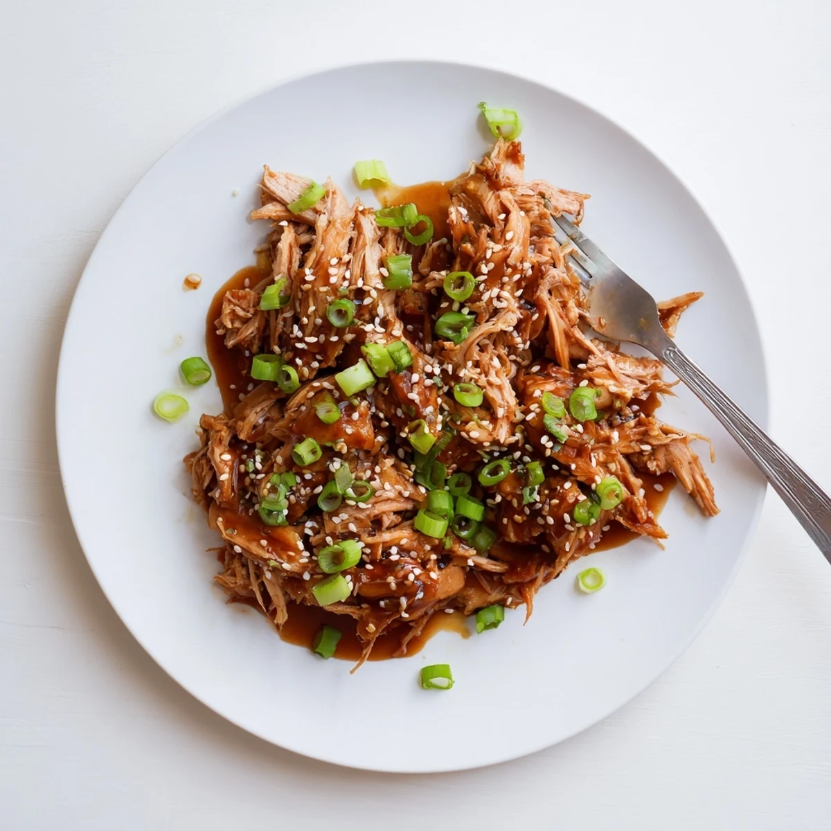 Golden Crockpot Teriyaki Chicken pieces coated in glossy homemade sauce and garnished with fresh green onions