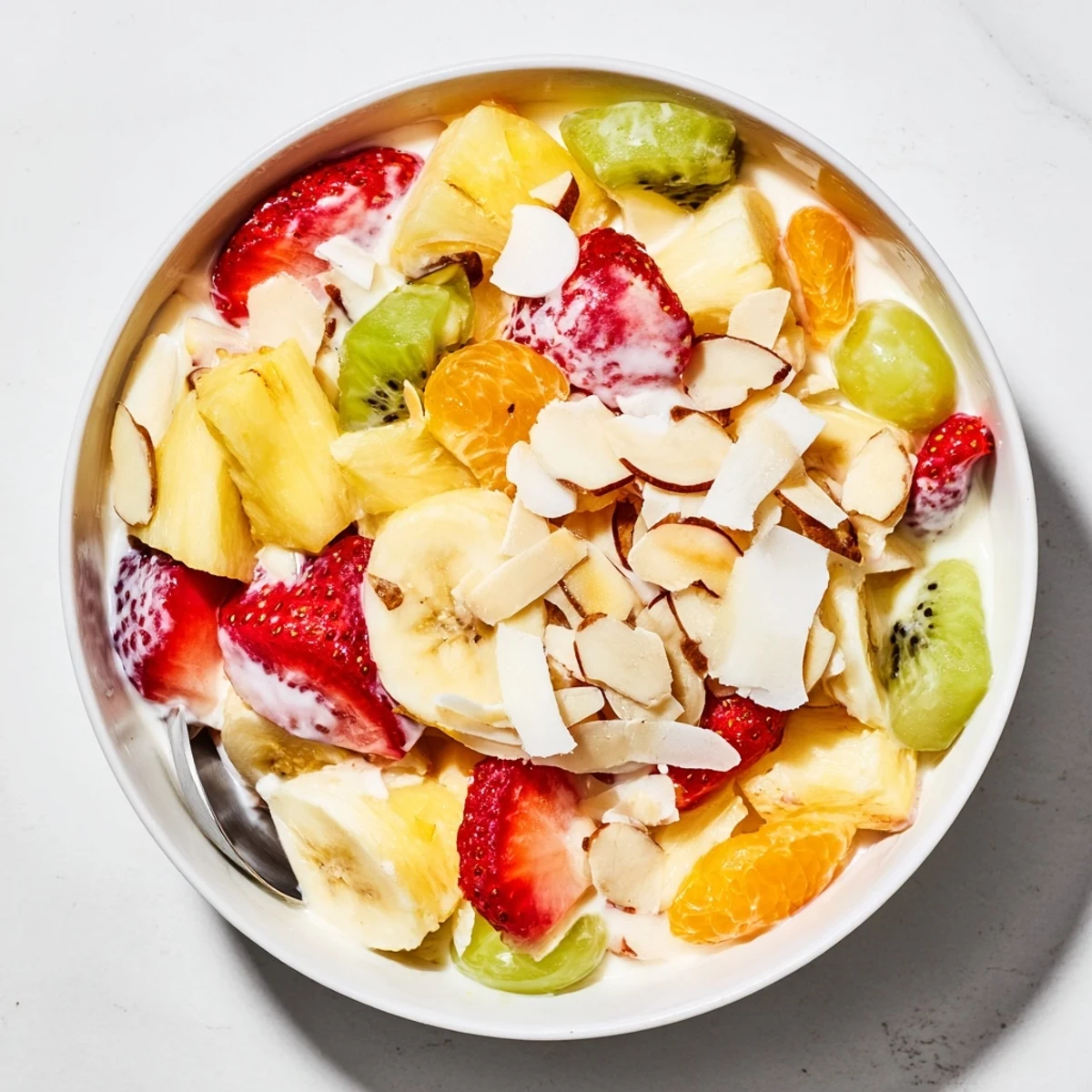 Refreshing creamy fruit salad with kiwi, mandarin oranges, and banana slices coated in vanilla cream