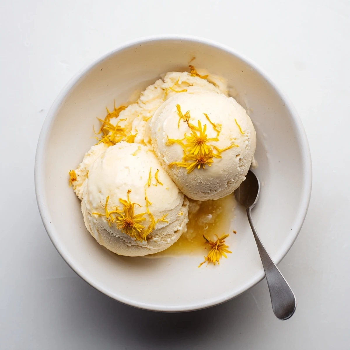 Creamy dandelion honey ice cream scoop drizzled with golden honey and fresh petals
