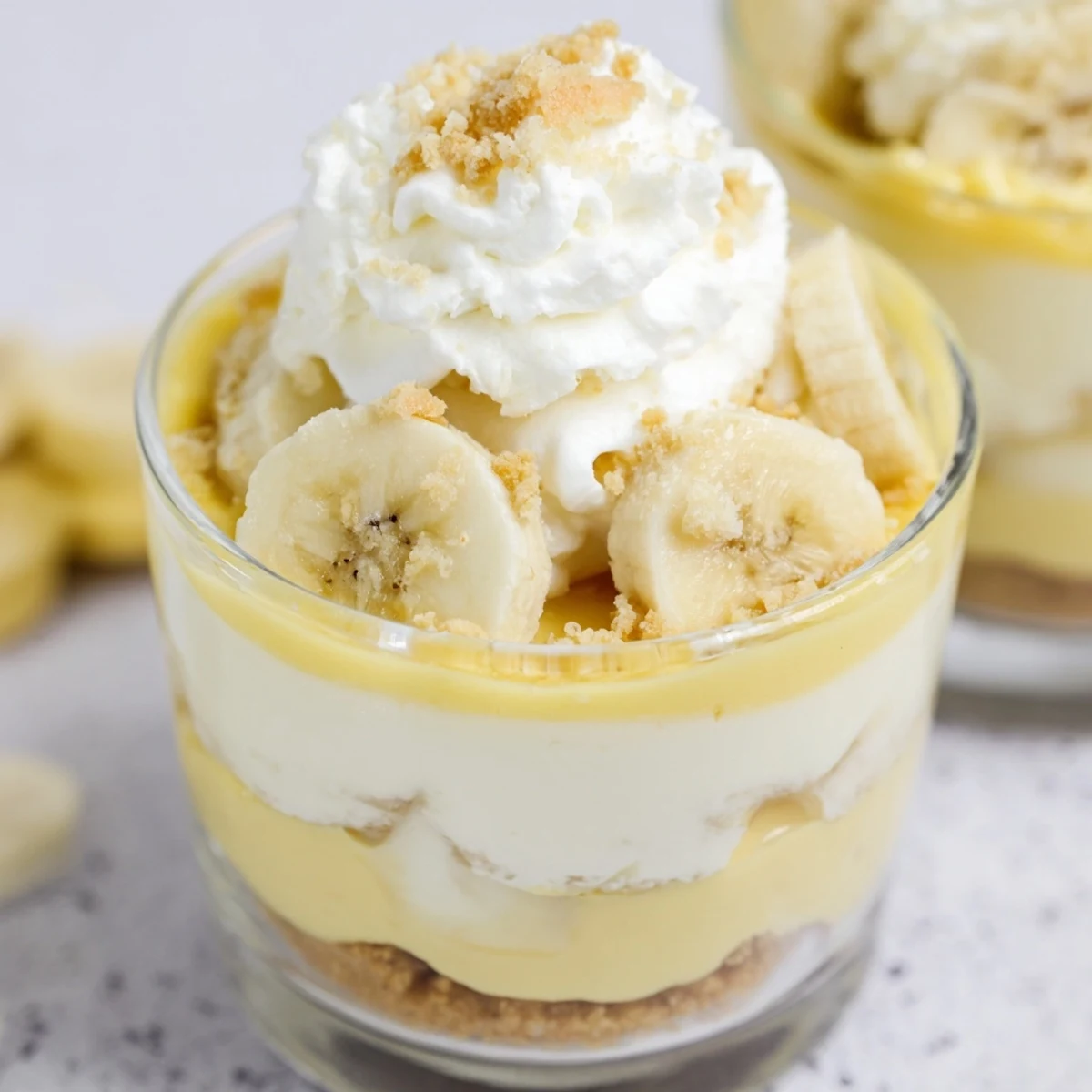 Individual no bake banana pudding cheesecake cups featuring layers of silky filling and crunchy golden crust