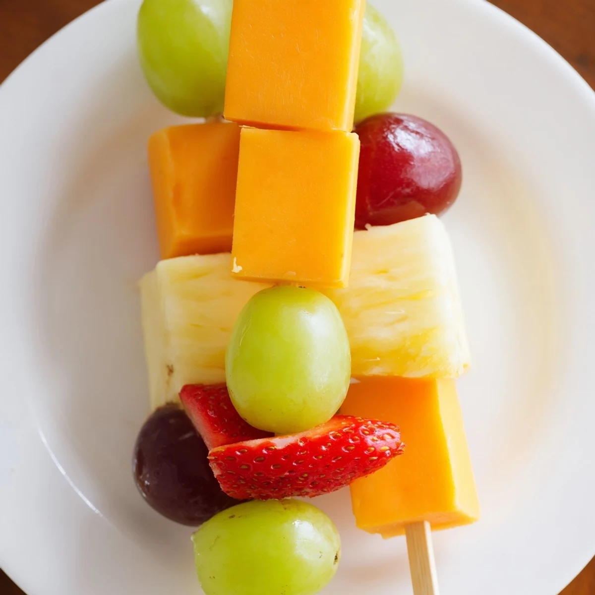 Colorful fruit and cheese kabobs arranged on platter with fresh mint garnish
