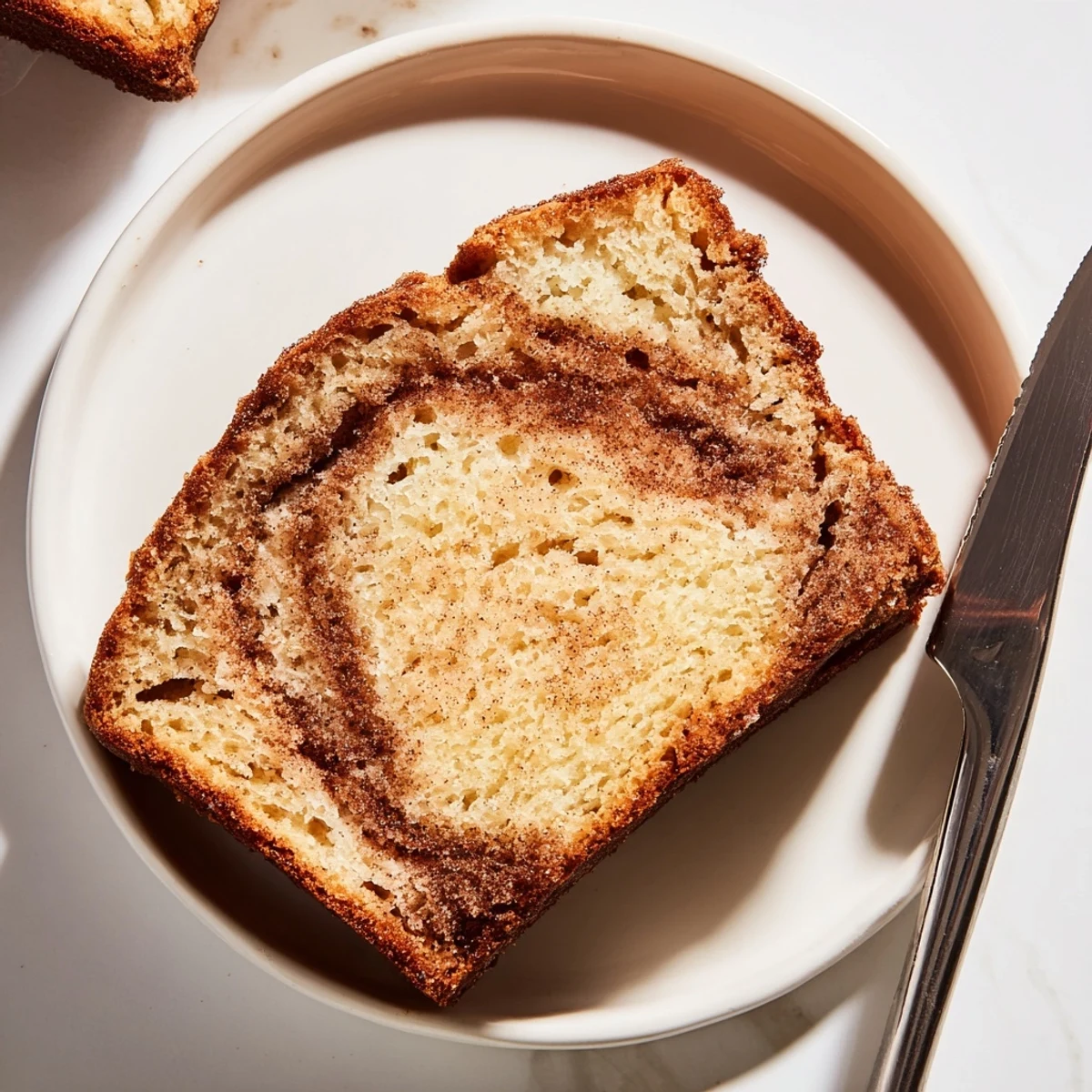 Golden slice of snickerdoodle banana bread with a warm cinnamon-sugar swirl