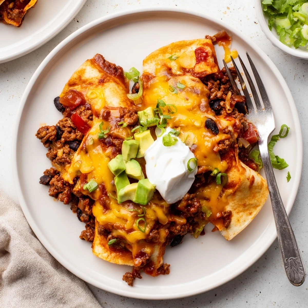 One-pan Beef Skillet Enchiladas served hot, garnished with avocado and sour cream
