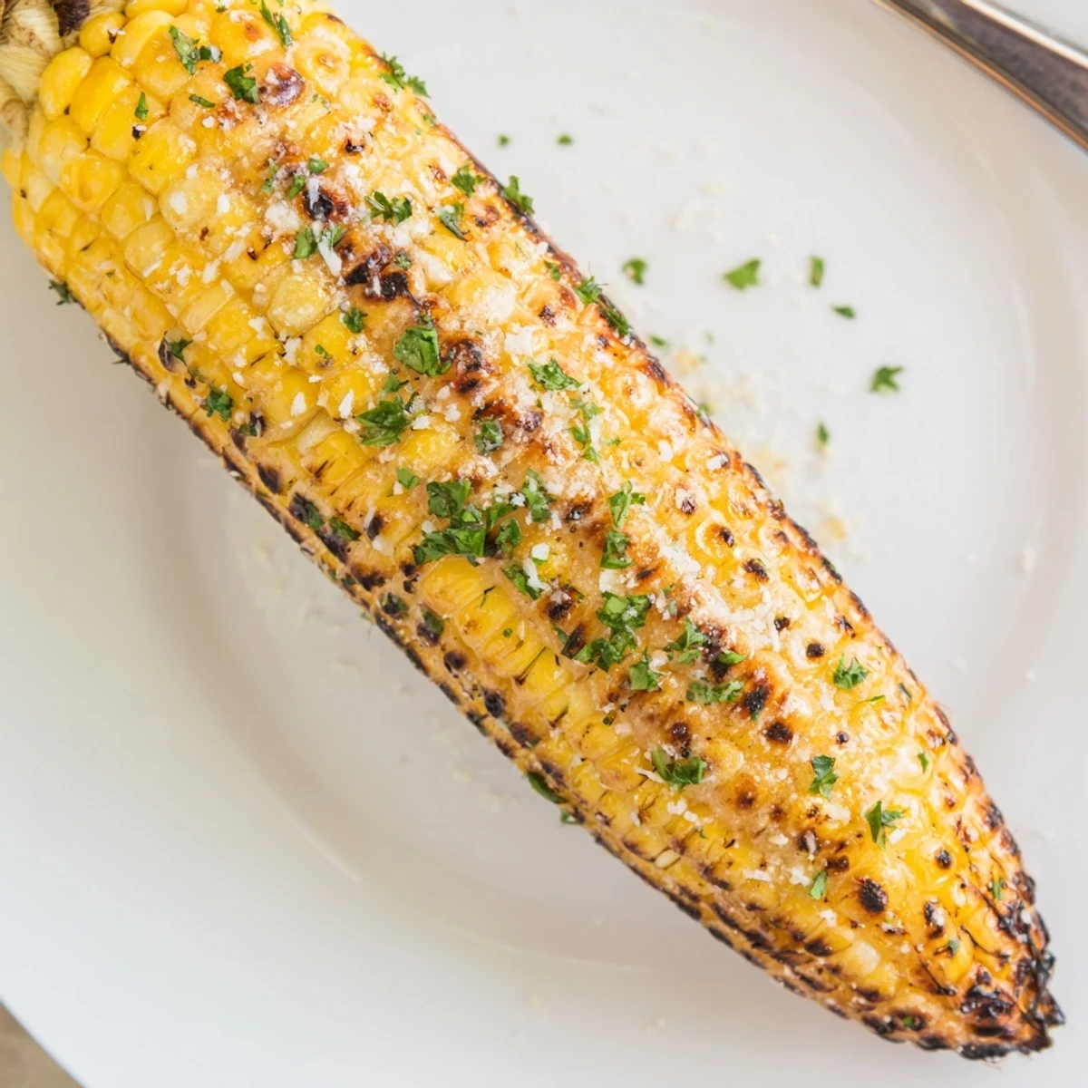 Close-up Garlic Parmesan Corn On The Cob sprinkled with fresh parsley, steaming.  
