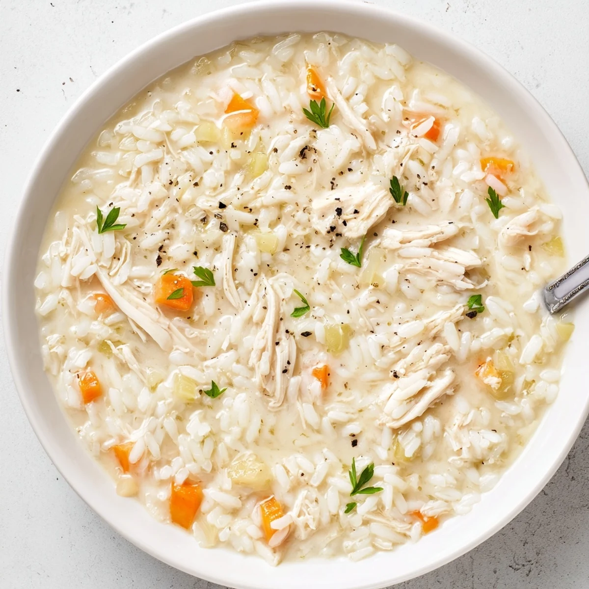 Warm bowl of Creamy Chicken Rice Soup, silky broth, tender rice, parsley