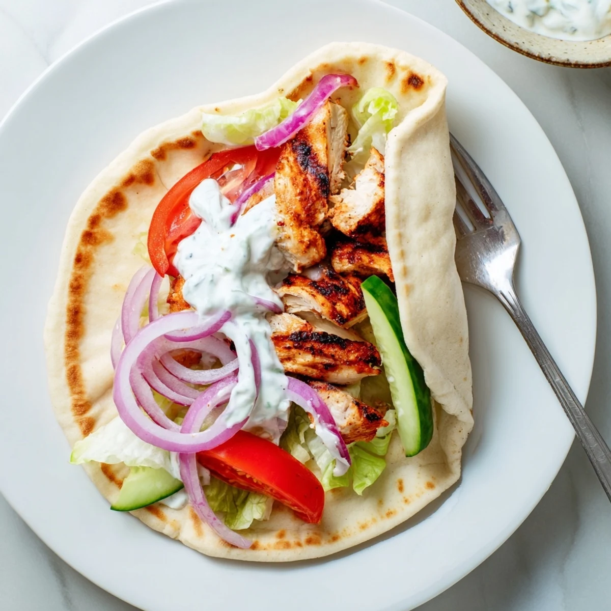 Mediterranean-style Greek Grilled Chicken Pita wrapped with marinated chicken, shredded lettuce, cucumber, and creamy garlic yogurt sauce.
