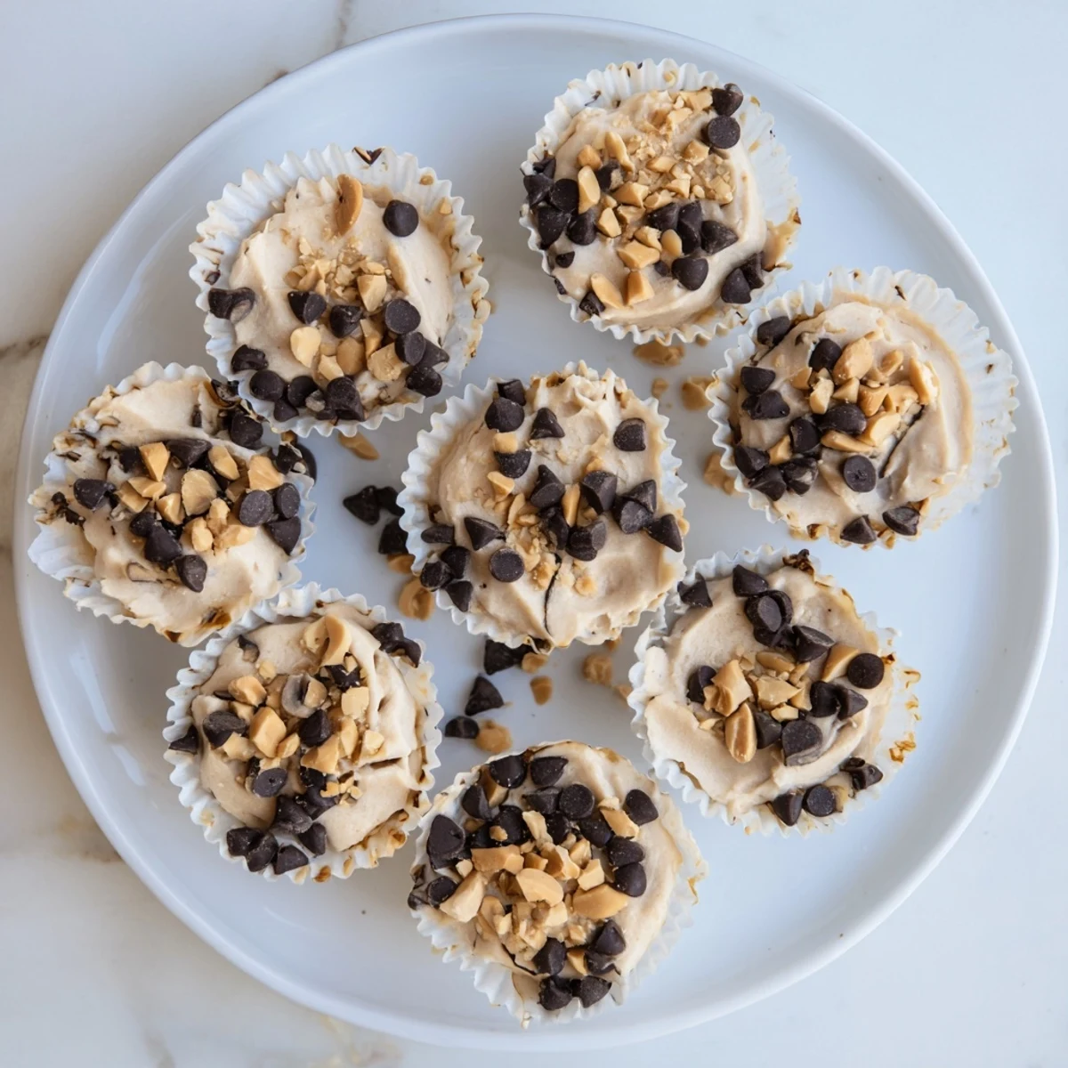 Frozen peanut butter Greek yogurt bites arranged on a white plate with a drizzle of chocolate sauce and peanut garnish