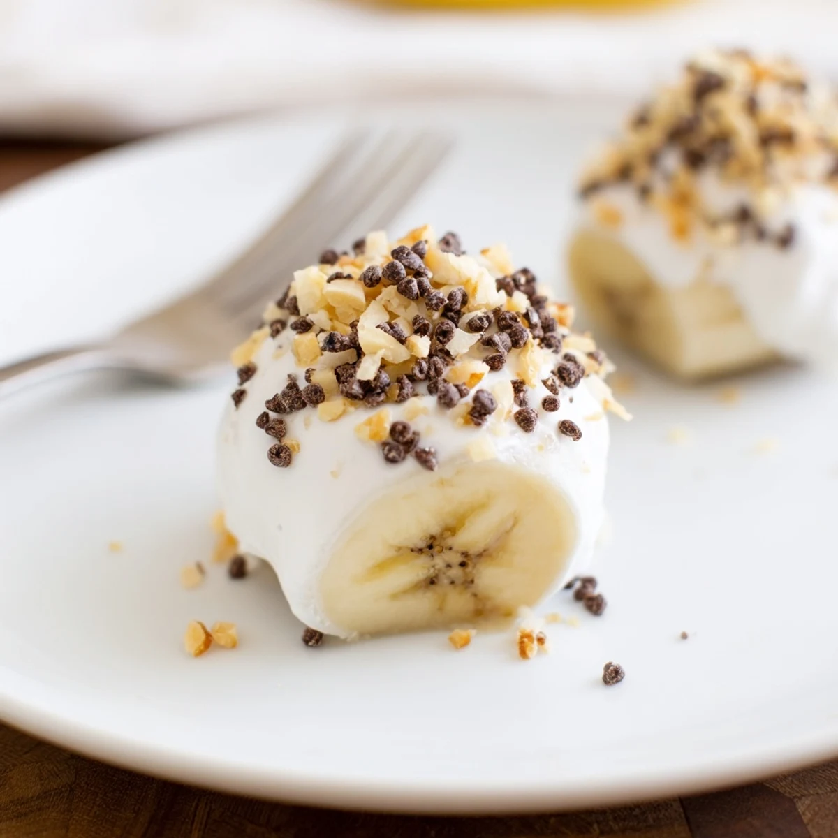 Frozen Banana Yogurt Bites on parchment, creamy coating, sprinkled with mini chips