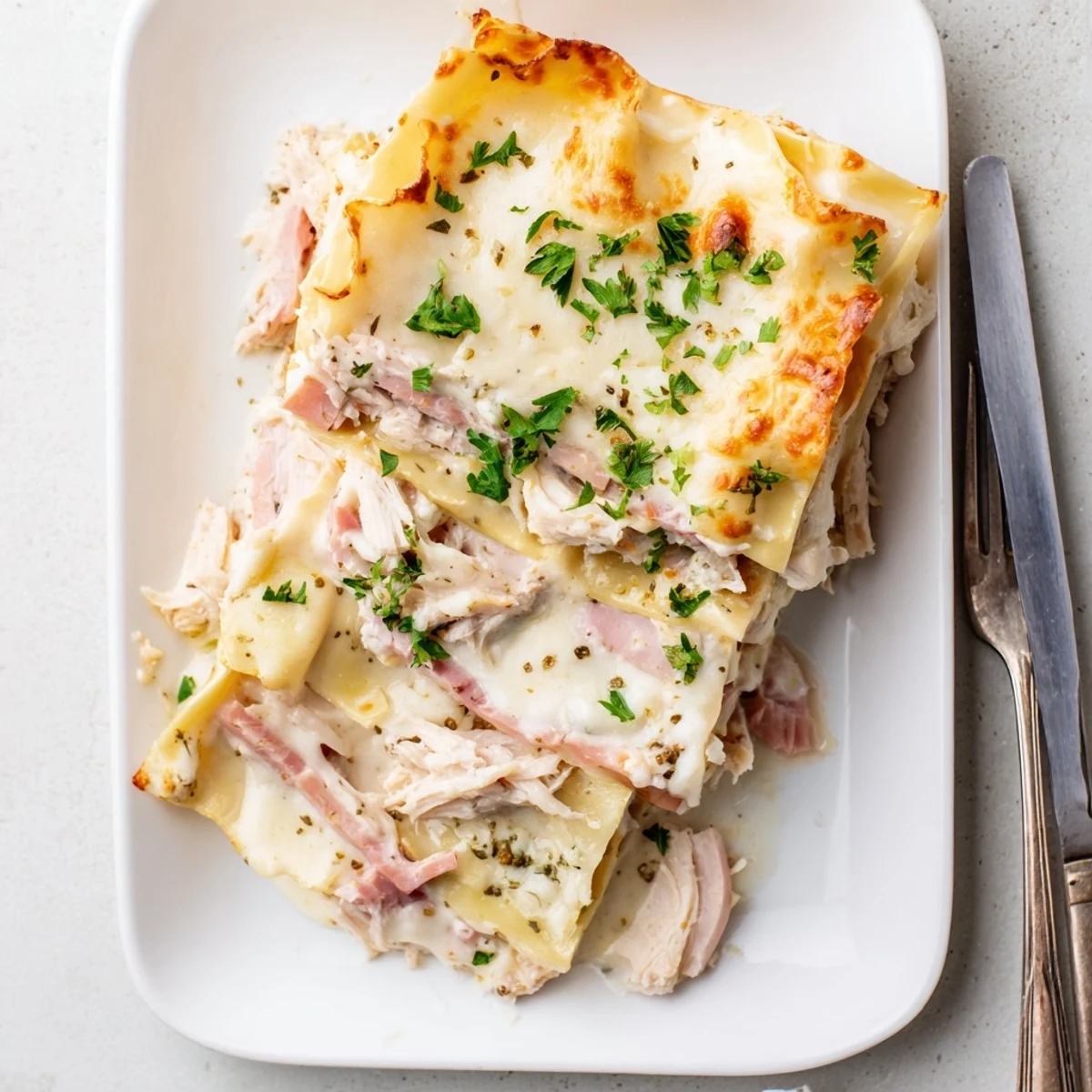 Golden baked Chicken Cordon Bleu Lasagna with layers of tender chicken ham and melted Swiss cheese bubbling under a crispy Parmesan topping