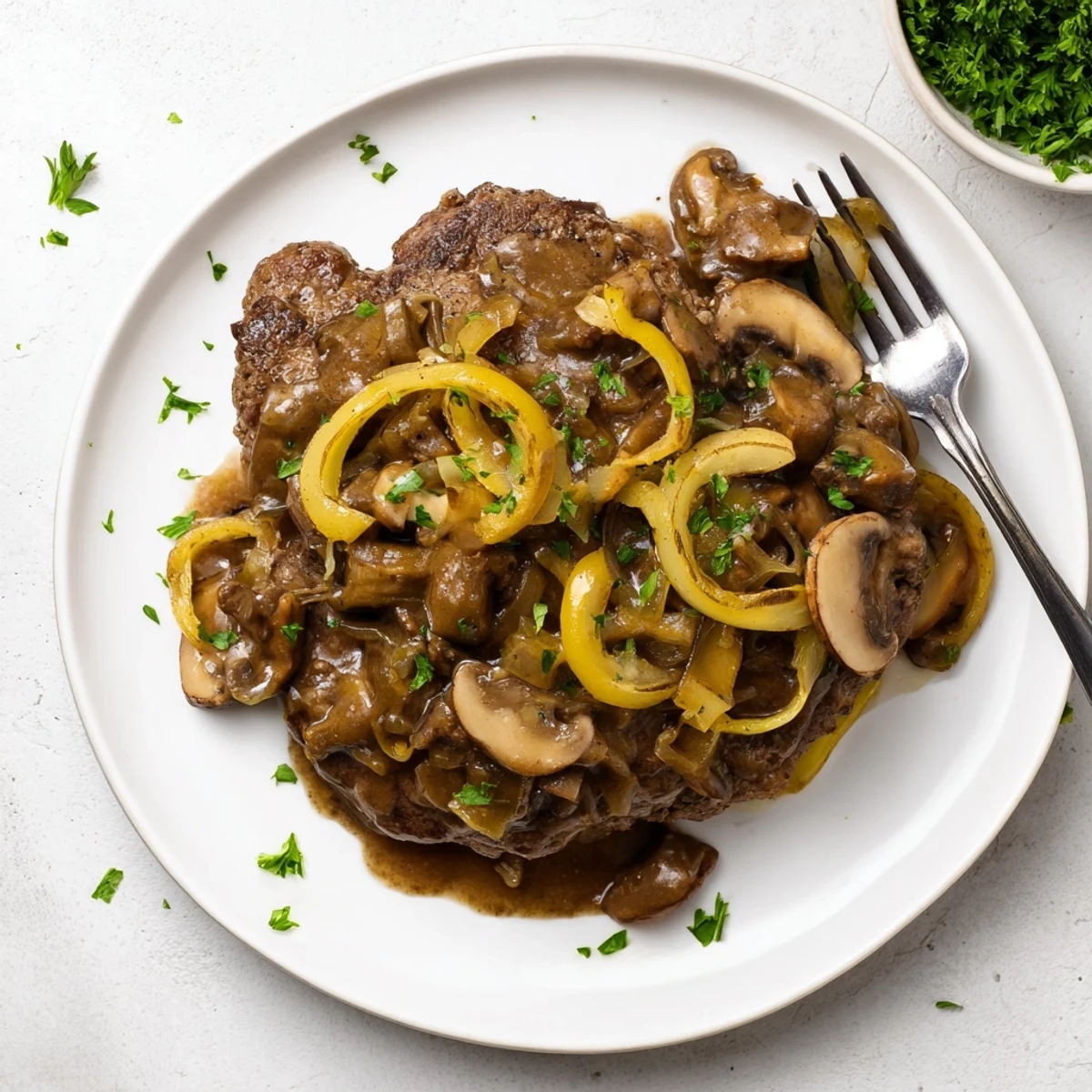 Fork-tender smothered cube steak dish topped with caramelized onions in creamy brown gravy