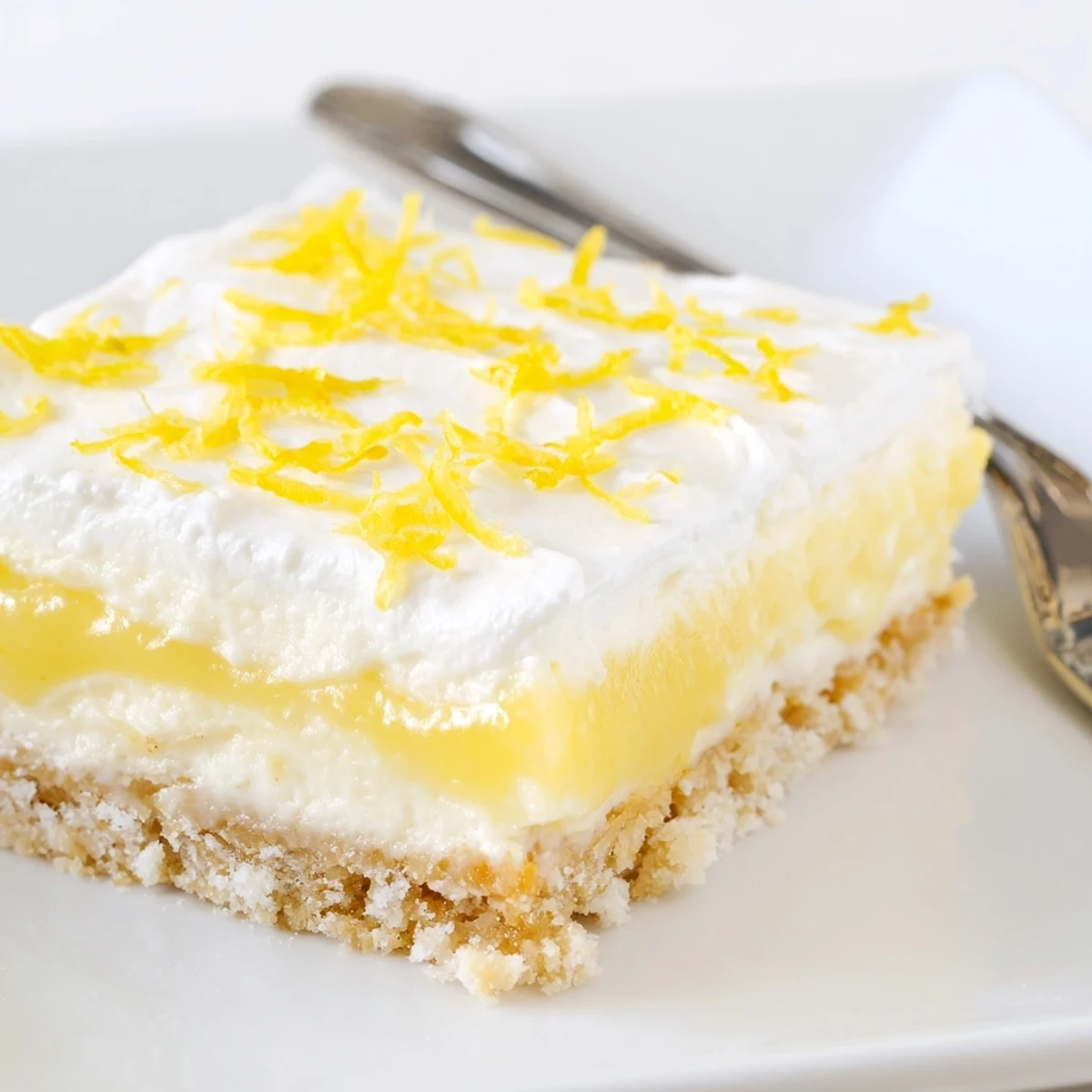 Slice of Lemon Lush Cake showing three layers, tangy, silky, cool