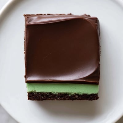Fudgy Shamrock Mint Brownies with Chocolate Ganache topped with silky ganache and a dusting of crushed peppermint.