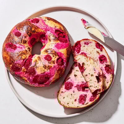 Fresh raspberries embedded in crusty sourdough bagels sprinkled with demerara sugar topping