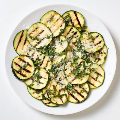 Plate of crispy grilled zucchini seasoned with garlic powder and finished with salty grated cheese